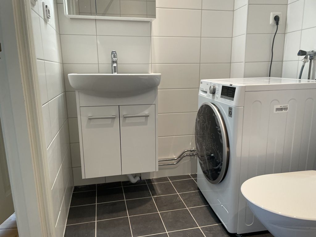 Helkaklat badrum med dusch och tvättmaskin